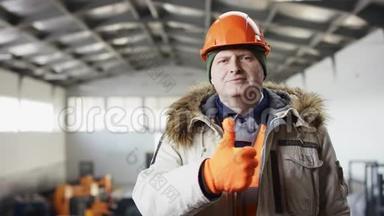 戴着安全帽、穿着工作服的人正站在机库中间，对着镜头竖起大拇指